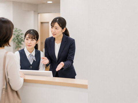 Manager supporting front desk staff while explaining a solution to a customer at reception