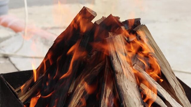 Glowing hot charcoal in barbecue grill pit with open flames close up background texture for bbq cooking and outdoor fire concept