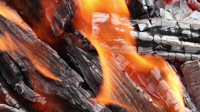 Glowing hot charcoal in barbecue grill pit with open flames close up background texture for bbq cooking and outdoor fire concept