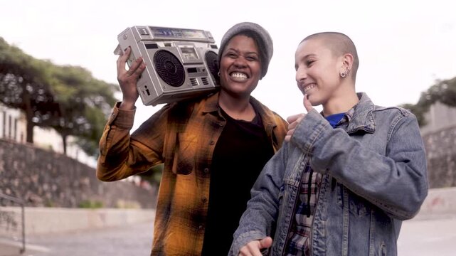 Happy multiracial friends having fun dancing and listening music with vintage boombox stereo