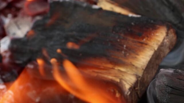 Glowing hot charcoal in barbecue grill pit with open flames close up background texture for bbq cooking and outdoor fire concept