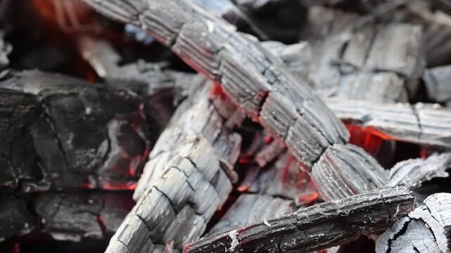 Glowing hot charcoal in barbecue grill pit with open flames close up background texture for bbq cooking and outdoor fire concept