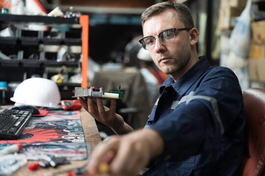 Male electrician engineer using soldering iron repairing electronic printed circuit board. Electrician checking, maintenance connecting electronic components on operation electric system