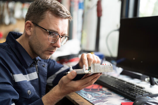 Male electrician engineer using soldering iron repairing electronic printed circuit board. Electrician checking, maintenance connecting electronic components on operation electric system