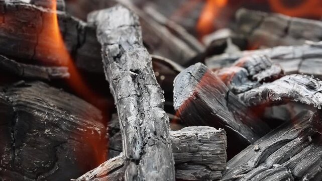 Glowing hot charcoal in barbecue grill pit with open flames close up background texture for bbq cooking and outdoor fire concept