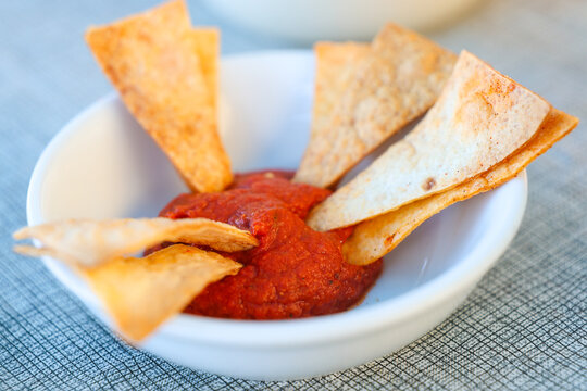 Crispy tortilla chips served with rich Santorini tomato paste in a white bowl, highlighting the vibrant color and authentic Mediterranean flavor of traditional Greek island cuisine.