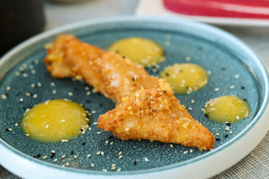 Golden fried cheese drizzled with honey and sprinkled with sesame seeds on a blue plate, combining sweet and savory flavors in a beautifully plated Mediterranean appetizer from Santorini.