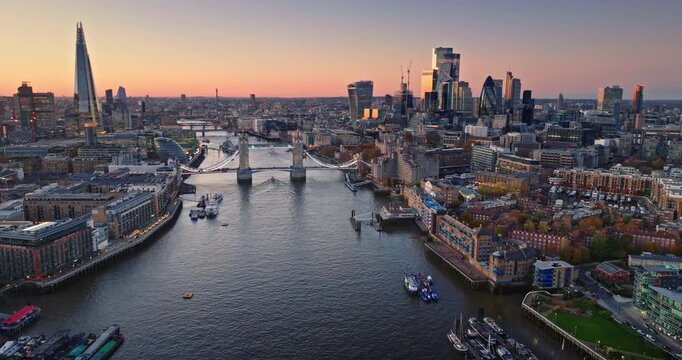Aerial London's urban landscape at sunset with its iconic skyline and flowing River Thames, featuring famous landmarks like Tower Bridge and The Shard. Travel and explore England capital modern city