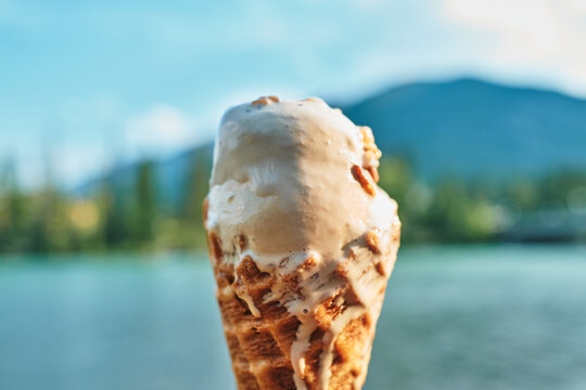 Melting ice cream cone with a lake and mountains behind