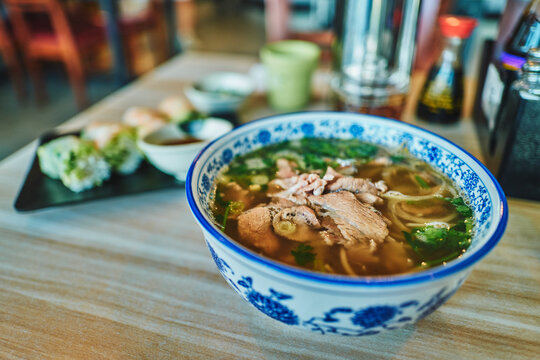 Vietnamese restaurant table with pho, spring rolls, and condiments
