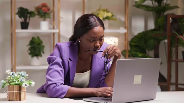 African businesswoman thinking, working from home on her laptop in a modern office setup