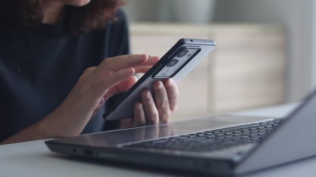 Young woman using smartphone and laptop in home office. Mobile phone in hand, social media, communication, typing chat online, Female relax, technology and using phone with mobile app, email, contact.