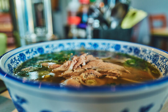 A full bowl of pho with condiments in the background