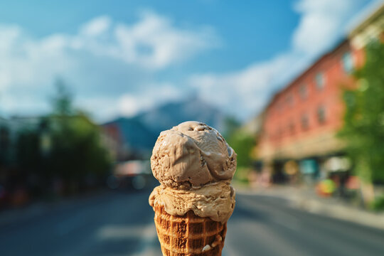 Chocolate ice cream cone held up on a sunny main street