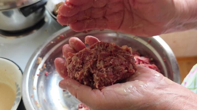 Elderly woman's hands skillfully forming homemade beef meatballs, shaping raw ground meat into perfect patties for a traditional family recipe in the kitchen