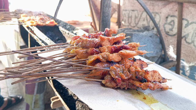 Indonesian chicken satay skewers grilled over traditional charcoal street food