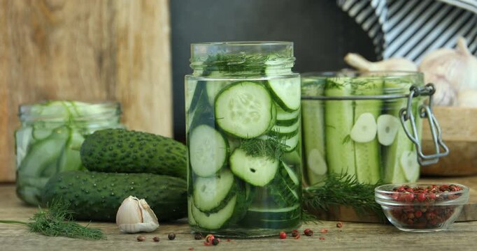 Taking pickled cucumber from jar at wooden table, closeup