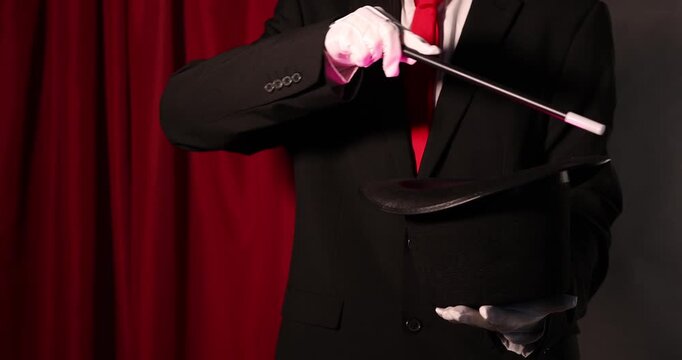 Magician showing trick with wand and top hat on stage, closeup