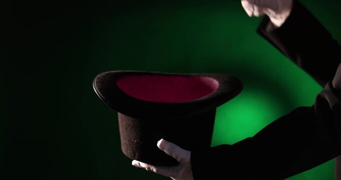 Magician showing trick with wand and top hat on stage, closeup