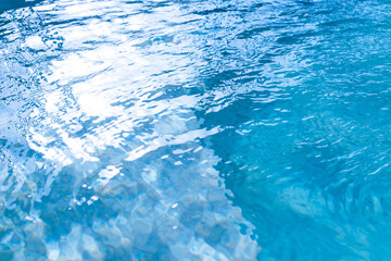 Fototapeta premium Blue water blurred surface with sunlight reflection and swimming pool ripples. Real photo non Ai generative