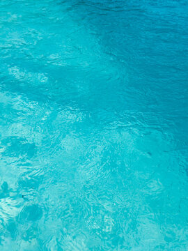 Blue water blurred surface with sunlight reflection and swimming pool ripples. Real photo non Ai generative