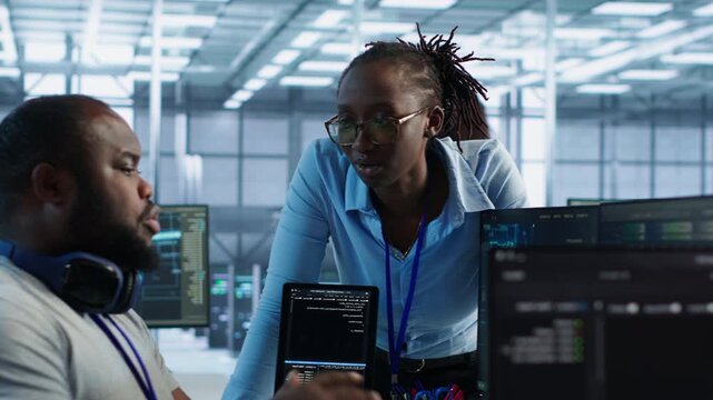 IT specialist talking with coworker while tracking AI supercomputers as highlighting data protection, network security and infrastructure risk.