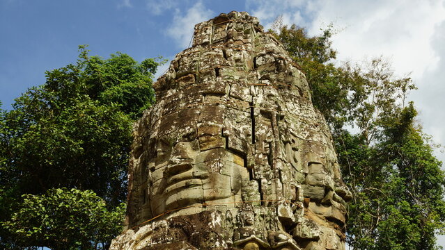 Close-up of ancient stone tower with giant carved face in Angkor