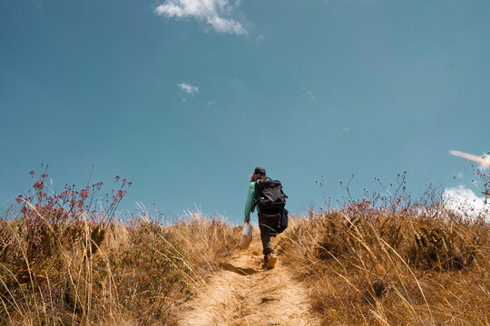 Sabrinsky Desert, Mosquera, Colombia. September 19, 2024. Man in the mountain. A low-angle shot ascending a narrow dirt path under a clear sky, surrounded by dry grass and wildflowers.