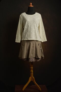 Cream knitted sweater with textured on brown skirt displayed on a dress form