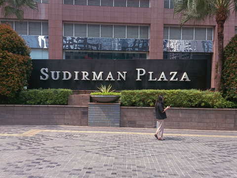 Jakarta, Indonesia, July 22, 2026: A unknown walks past the Sudirman Tower logo signage in Jakarta, Indonesia.