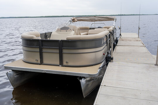 Modern pontoon boat docked at a wooden pier