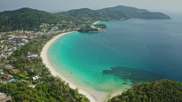 Tropical coastline panorama featuring the crescent sandy beach and clear turquoise waters of Kata Bay, surrounded by green hills and waterfront resorts, highlighting a popular travel destination