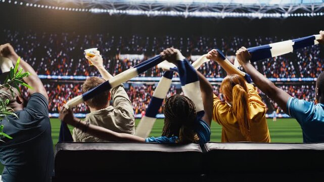 Soccer supporters wave scarves during a football game in the living room as immersive TV broadcast makes them feel closer to the stadium pitch while football fans chant loudly with crowd energy.