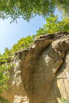Majestic rocky cliffs and towering trees against blue sky. View of the rocks in Kislovodsk, Russia.
