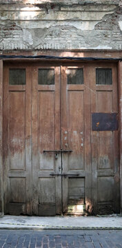Old weathered wooden double door in crumbling masonry wall