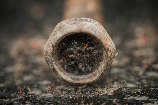 Macro close up shot of a weathered rusty metal bolt head with stamped numbers and gritty textured background