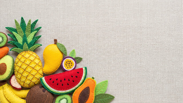 Handcrafted felt fruits, including a pineapple, watermelon, and avocado, arranged in the bottom corner on a textured canvas background with ample copy space.