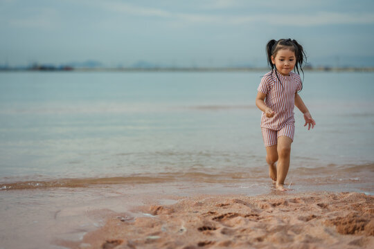happy preschool child girl running on sea beach in Pattaya, Thailand