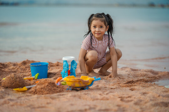 happy preschool child girl playing sand toy on sea beach in Pattaya, Thailand
