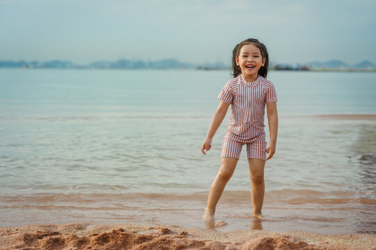 happy preschool child girl playing on sea beach in Pattaya, Thailand
