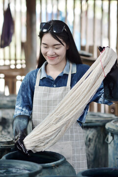 A skilled artisan prepares cotton fibers for traditional indigo dyeing in Sakon Nakhon, Thailand.