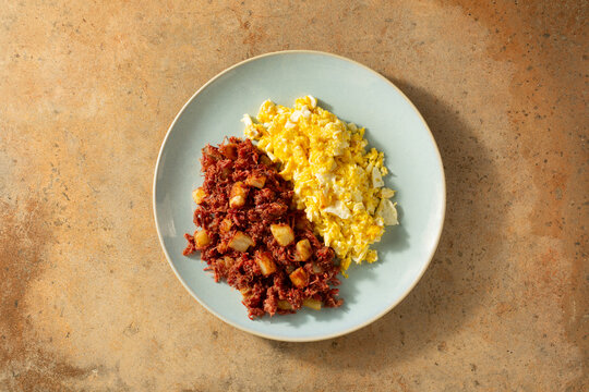 A top down view of a plate of corned beef hash and scrambled eggs.