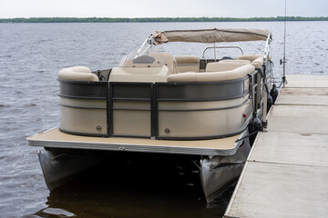 Modern pontoon boat docked at a wooden pier © Olha Semeniv