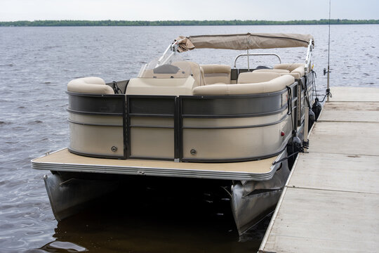 Modern pontoon boat docked at a wooden pier
