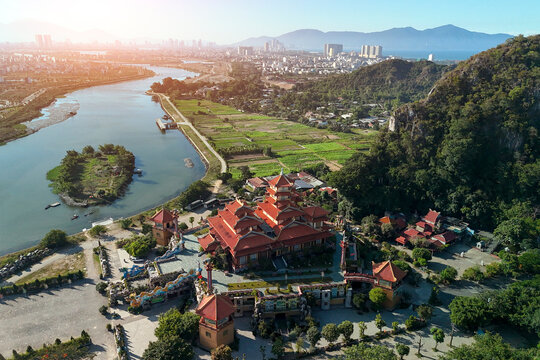 Traditional temple buildings surrounded by green fields and river water near the coastal city of Da Nang in Vietnam during daytime