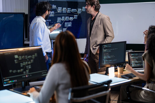 A wide view of a high-tech operations control center with staff working at rows of illuminated workstations, inside a high-technology research laboratory lit by the cool blue glow of the.