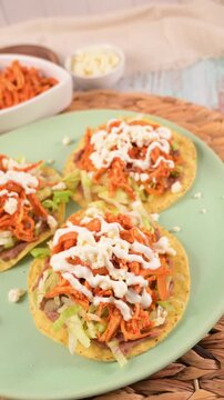 Aerial view of chicken tinga tostadas with lettuce, cream, and cheese