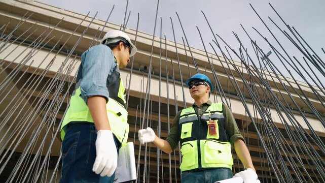 Two construction engineers shaking hands at an infrastructure construction site, representing successful collaboration, project approval, and professional partnership.
