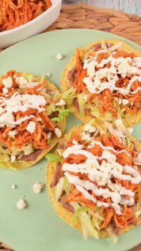 Mexican food. Three crunchy corn tostadas with chicken tinga, refried beans and lettuce