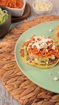 Mexican shredded chicken tostadas topped with fresh cheese and sour cream